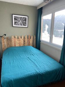 um quarto com uma cama azul e uma janela em Appartement 50m2 vue imprenable avec garage draps et serviettes compris em Villard-de-Lans