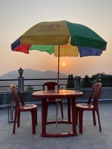 a table and two chairs under an umbrella at Graham Hill’s Stay in Darjeeling