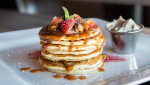 a stack of pancakes with strawberries and syrup on a plate at The Blyde Riverwalk Estate in Pretoria