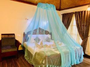 a bedroom with a bed with a blue mosquito net at Maadathil Beach Resort in Varkala