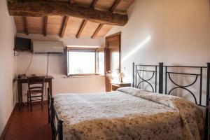 a bedroom with a bed and a desk and a window at Poggio Al Vento in Castiglione dʼOrcia