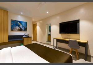 a bedroom with a bed and a desk with a television at Hotel Elite Inn- In Front Of Railway Station in Kolhapur