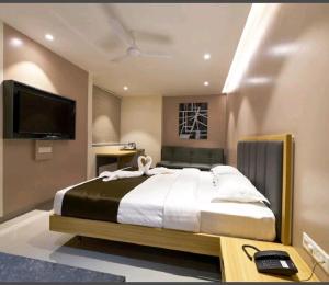 1 dormitorio con 1 cama grande y TV de pantalla plana en Hotel Elite Inn- In Front Of Railway Station, en Kolhapur
