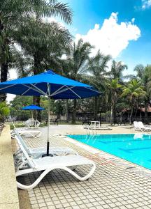 una sombrilla azul y sillas junto a la piscina en Cinta Sayang Resort, en Sungai Petani