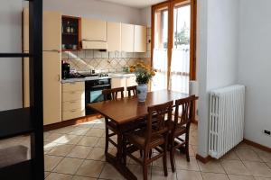 a kitchen with a wooden table with chairs and a vase of flowers at Confortevole monolocale faentino con terrazza in Faenza