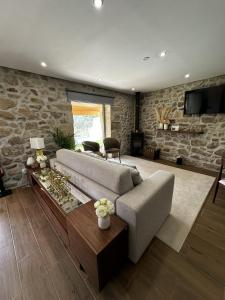 een woonkamer met een bank en een stenen muur bij Quinta de Gandarem in Torre de Moncorvo
