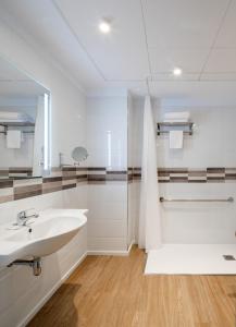 La salle de bains blanche est pourvue d'un lavabo et d'un miroir. dans l'établissement Apartamentos Forum Ceao, à Lugo