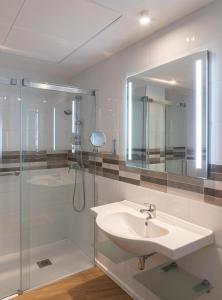 bagno con lavandino, doccia e specchio di Apartamentos Forum Ceao a Lugo
