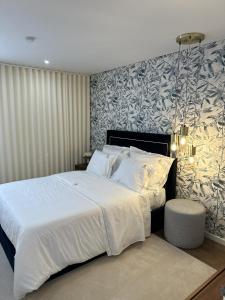 Un dormitorio con una gran cama blanca y una pared estampada en Quinta de Gandarem, en Torre de Moncorvo