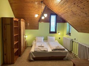 a bedroom with a large bed and a wooden ceiling at Galéria Vendégház in Mezőkövesd