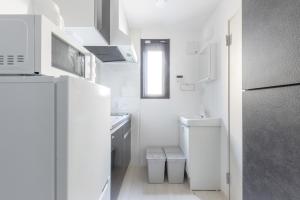 ein weißes Badezimmer mit einem Waschbecken und einem Kühlschrank in der Unterkunft APB高円寺 in Tokio