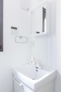 ein weißes Badezimmer mit einem Waschbecken und einem Spiegel in der Unterkunft APB高円寺 in Tokio