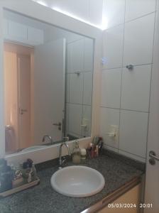 uma casa de banho com um lavatório e um espelho grande em Aconchegante com Piscina em Laguna