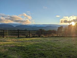 a fence in a field with the sunset in the background at Grade II Lodge House 2 Bedroom in Trawsfynydd