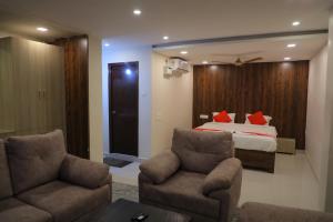 Habitación de hotel con 1 cama y 2 sillas en Nakshatra grand, en Tirupati