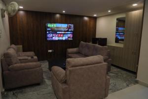 a living room with two chairs and a flat screen tv at Nakshatra grand in Tirupati