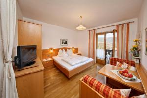 ein Hotelzimmer mit einem Bett und einem TV in der Unterkunft Humblhof in Algund