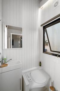 a white bathroom with a toilet and a sink at Campbells Cottage - Farm Stay Victoria 