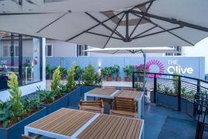 un patio con mesas y sillas bajo una sombrilla blanca en Olive Hotel Brookefield by Embassy Group, en Bangalore
