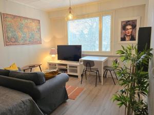 uma sala de estar com um sofá e uma mesa com uma televisão em Studio Porin Otso, home away home in Pori city center em Pori