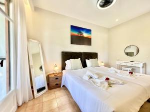 a bedroom with a large white bed and a mirror at Beachfront Suites GardenMare by DadoVillas in Litherés