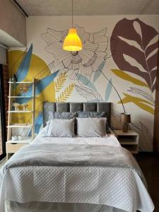 1 dormitorio con 1 cama y una pared con flores en Diua - Artistic and Bohemian apartment, en Guatemala