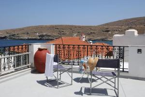 a balcony with two chairs and a vase on a house at Paraporti Rooms in Andros