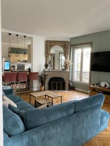 - un salon avec un canapé bleu et une cheminée dans l'établissement Logement en Hôtel Particulier - 3mn Paris et métro, à Boulogne-Billancourt