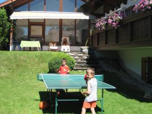 Dois rapazes a jogar pingue-pongue num quintal. em Apartment in the Allg u with view of the Bavarian Alps em Bernbeuren