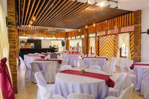 une salle à manger avec des tables et des chaises blanches dans l'établissement D' Elmer's Resort and Convention Hotel, à Dinadiwan