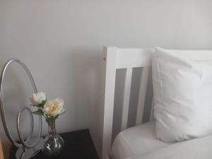 a vase with flowers on a table next to a bed at Peaceful Home in Surbiton, Surrey, Greater London- Free parking in Surbiton