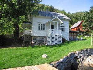 a small white house with a stone wall at "Butikken" - sea cabins in Ulvik