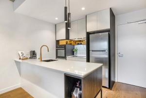 a kitchen with a counter and a refrigerator at Stay Near Botanic Garden with Gym, Sauna & Parking in Melbourne