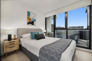 a bedroom with a large bed and a large window at Stay Near Botanic Garden with Gym, Sauna & Parking in Melbourne