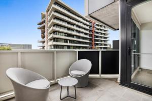 un balcón con 2 sillas y un edificio en Stay Near Botanic Garden with Gym, Sauna & Parking en Melbourne