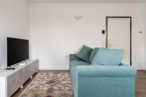 sala de estar con sofá azul y TV en Bilocale con balcone vicino palazzo del ghiaccio en Milán