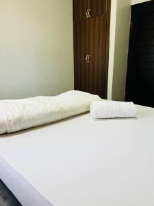 2 białe łóżka w sypialni z szafą w obiekcie Malaika Homes Jinja w mieście Jinja