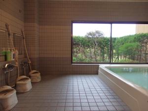 ein Bad mit einer Badewanne, 2 WCs und einem Fenster in der Unterkunft Forest Villa YUMESUZU フォレストヴィラ夢寿々 in Kaizu