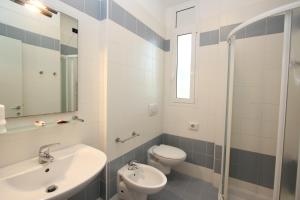 bagno con lavandino, servizi igienici e specchio di Hotel Laura a Bibione