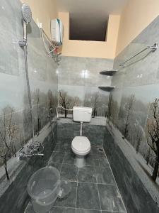 a bathroom with a toilet and a shower with trees on the wall at Y STAY HOMESTAY in Tirupati