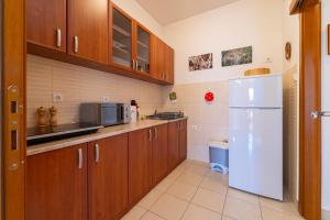 eine Küche mit Holzschränken und einem weißen Kühlschrank in der Unterkunft Family One bedroom apartment with Panoramic city view in Budva