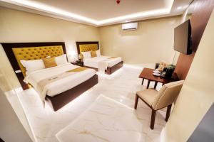una camera d'albergo con due letti e una televisione di Monaco Hotel a Taytay