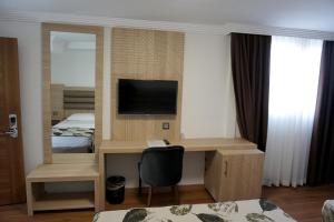 a room with a desk with a television and a bedroom at Mandalin Otel in Antalya