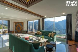 un soggiorno con divano verde e tavolo di StayVista at Orion Villa a Shimla