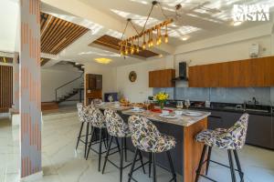 una cucina con una lunga isola con sgabelli da bar di StayVista at Orion Villa a Shimla