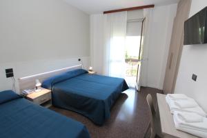 una camera d'albergo con due letti e una televisione di Hotel Laura a Bibione