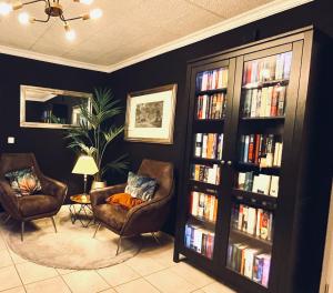 una sala de estar con 2 sillas y una estantería llena de libros. en Lot54 Deluxe Apartements, en Neidenbach