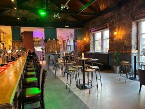 a restaurant with tables and chairs and a woman sitting at a bar at Paisley Central Apartment in Paisley