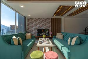 un soggiorno con divani blu e un tavolo di StayVista at Orion Villa a Shimla