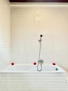 a white bath tub with red flowers in a bathroom at Bupon House Jepun Room in Gianyar